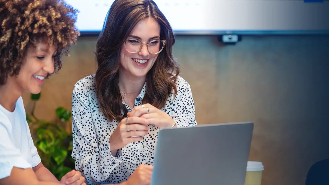 two happy female hr managers looking at their computer to assess gift card program 