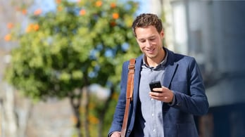 Happy businessman outside checking his phone 
