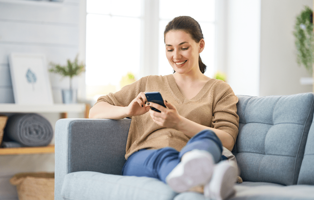 Woman on couch happy to receive a digital gift card after completing a survey.