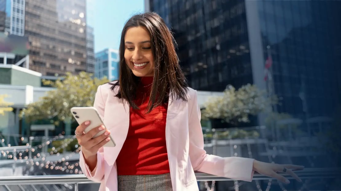 Smiling business woman holding mobile phone reading text message that just delivered an Apple gift card
