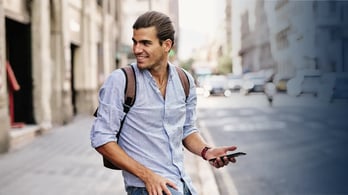 Young man smiling with smartphone at via laietana in Barcelona