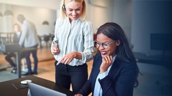 administrative assistant talking to her boss at her desk