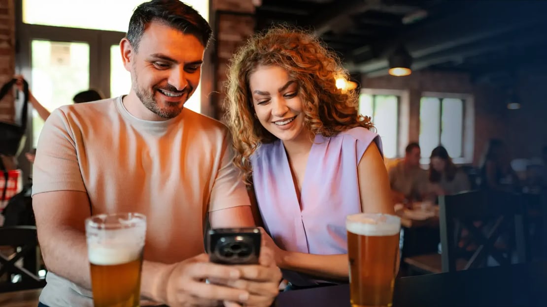 couple looking at a gift card on their phone at a casual dining restaurant