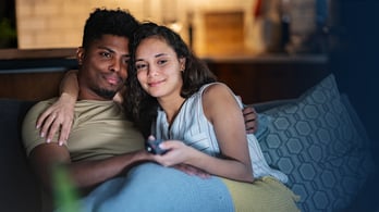 couple on couch watching a subscription service on tv