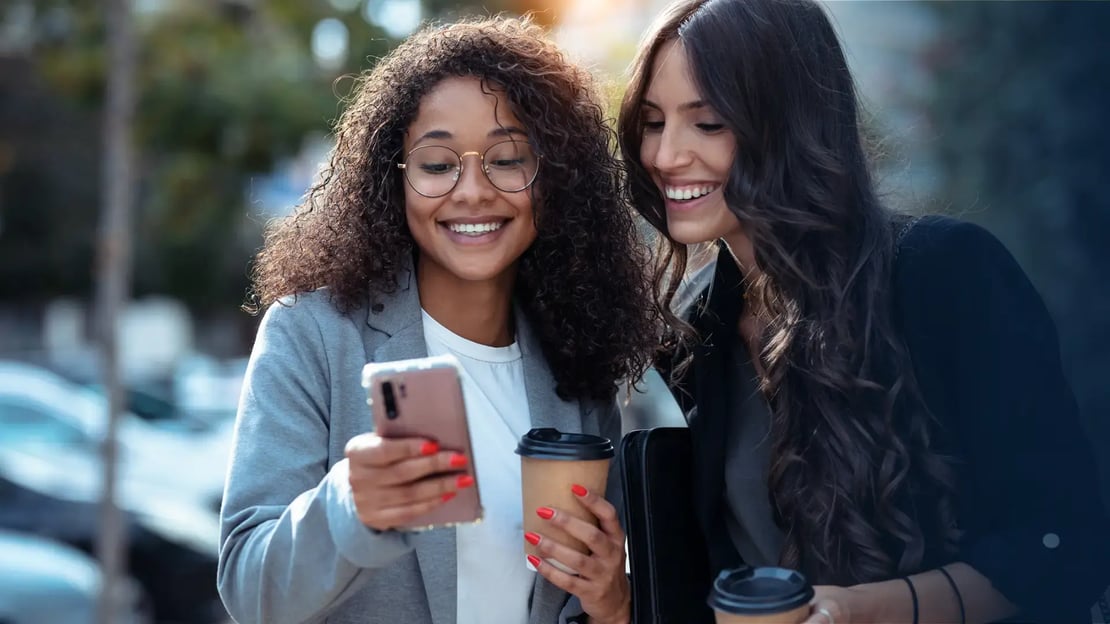 two female employes smiling and looking at a digital gift card received on their phone