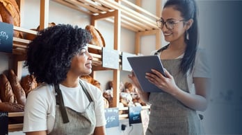 two small bakery owners discussing business looking at a table