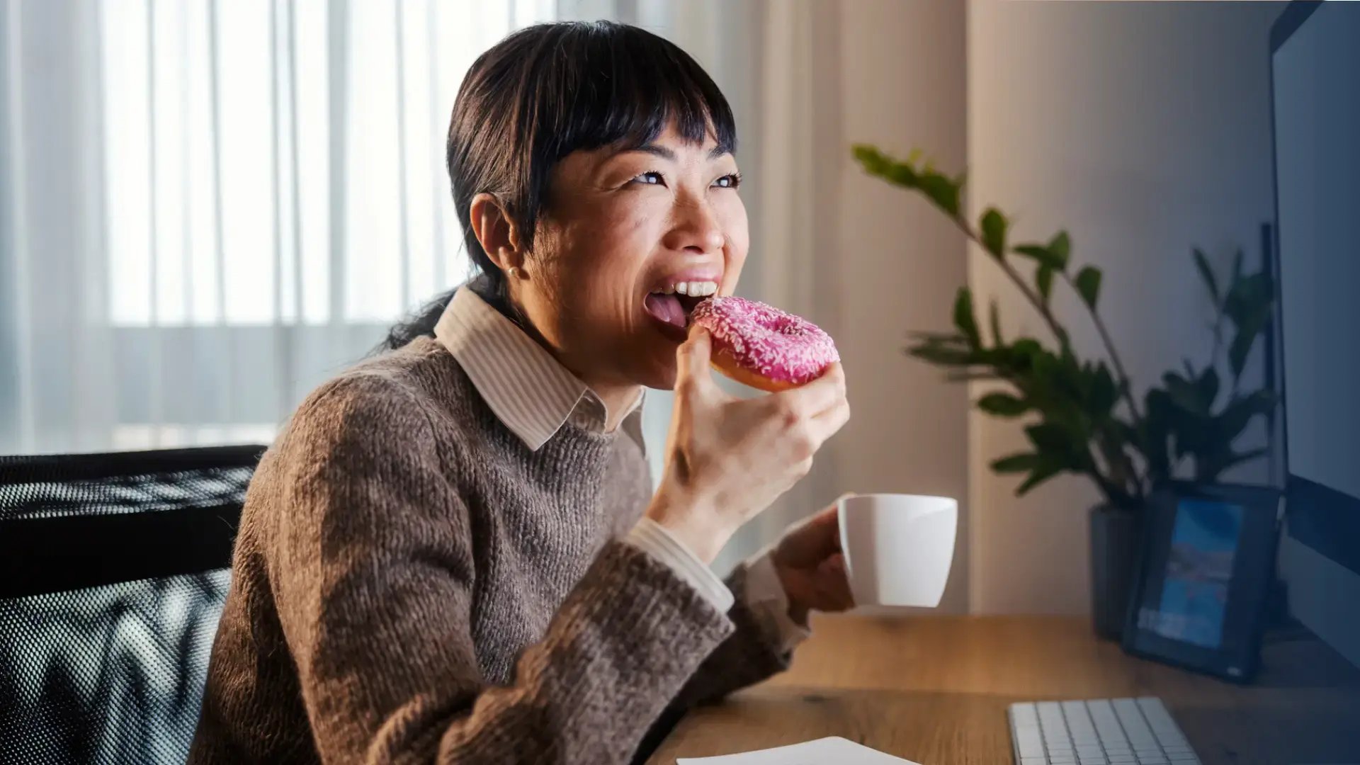 woman looking at her desktop screen and eating a tim hortons 