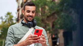 young man looking at a prepaid visa that was just emailed to his phone