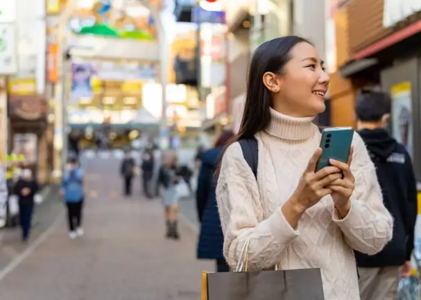 young woman receiving a gift card in her phone while walking in a big city (2)