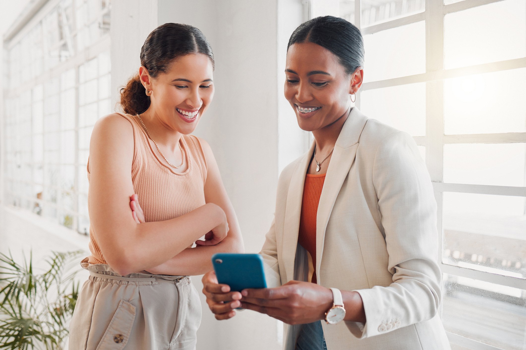 two happy female employees looking at a digital reward on the same phone