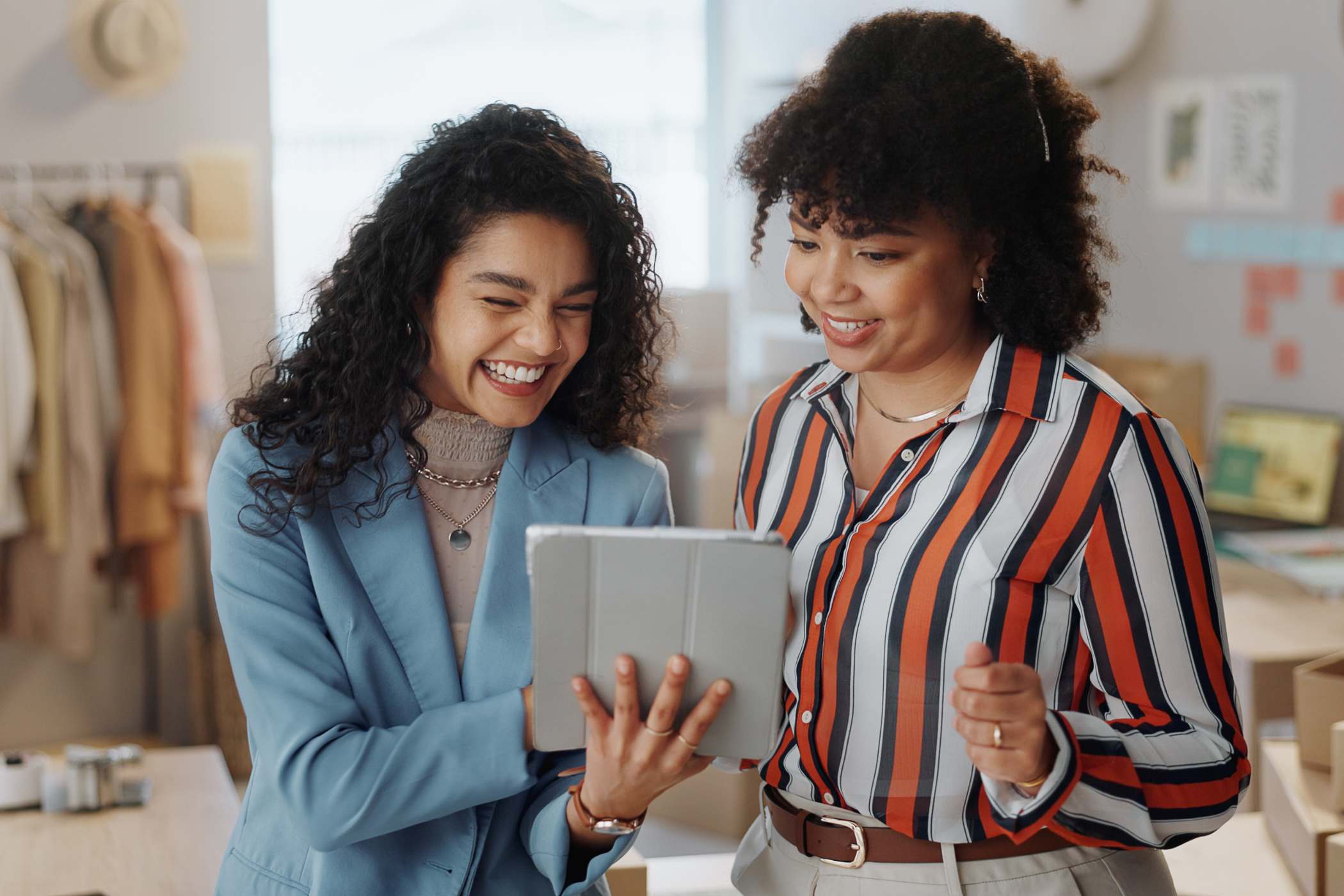 two business women smiling looking at digital tablet