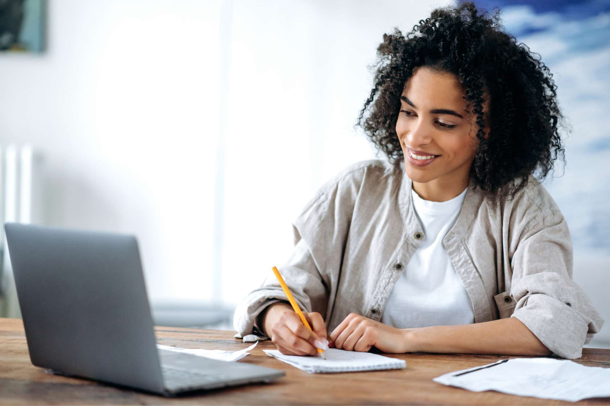 woman taking notes while watching an online lesson on her laptop